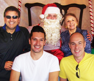 Festive smiles: Ernie Manouse (far left) gets in the holiday spirit with Santa, his mom, Adele Manouse, designer Jeff Koffler (front left), and his partner, Jackson Hearne.