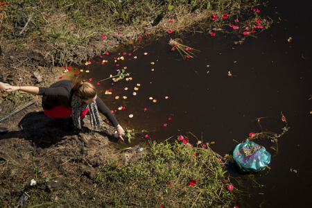 Friends float flowers and balloons into the water where Janie’s car went off of Church Road and sank into Slocum Creek.